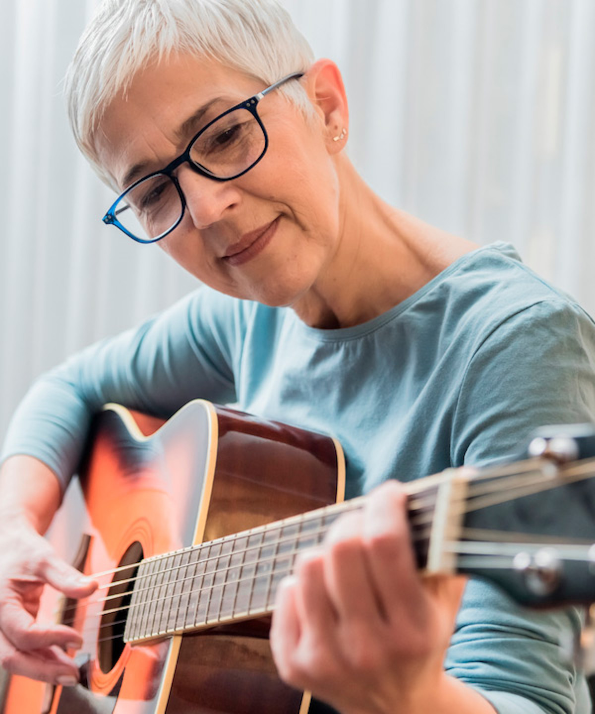 Kvinne spiller akustisk gitar med et smil